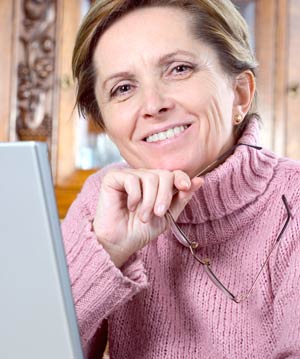 Photo of a smiling and confident older woman with dentures wearing a pink sweater